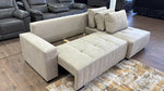 Beige sectional sofa with storage bench on a wooden floor.